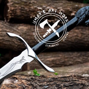 May include: A silver sword with a black handle and a horse engraved on the blade. The handle has a black circular design with the text "UMAR'S ART WORK" and the words "CREATE", "INNOVATE", "MOTIVATE" around the circle.