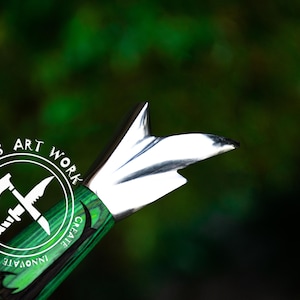 May include: A green and black knife handle with a silver blade. The handle has a circular design with the words "UMAR'S ART WORK" and the text "MOTIVATE INNOVATE CREATE".