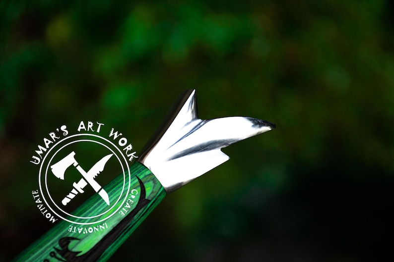 May include: A green and black knife handle with a silver blade. The handle has a circular design with the words "UMAR'S ART WORK" and the text "MOTIVATE INNOVATE CREATE".