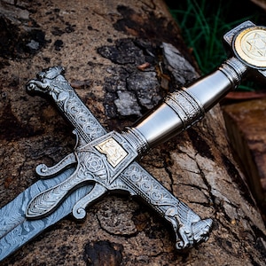 May include: A silver sword with intricate engravings and a gold-coloured Star of David on the pommel. The sword is resting on a piece of wood.