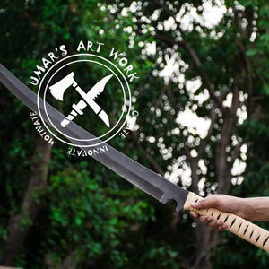 K&ouml;nnte beinhalten: Ein gro&szlig;es, schwarzes Schwert mit einer gebogenen Klinge und einem hellbraunen, umwickelten Griff. Das Schwert wird vor einem Hintergrund aus gr&uuml;nem Laub gehalten. Das Bild enth&auml;lt ein rundes Logo mit dem Text "UMAR'S ART WORK" und den W&ouml;rtern "MOTIVATE" und "INNOVATE".