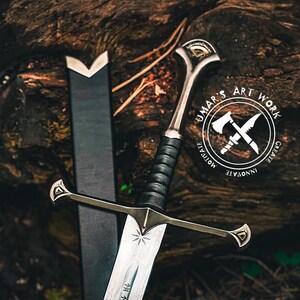 May include: A detailed image of a sword with a black handle and silver blade, resting against a dark sheath. The sword features a decorative hilt and crossguard. The image includes a logo that says "UMAR'S ART WORK" with the words "MOTIVATE", "INNOVATE", and "CREATE".