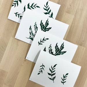 May include: Four white cards with green leaf illustrations printed on them. The cards are numbered 1/10, 2/10, 3/10, and 4/10.