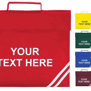 May include: A red school satchel with a handle and a flap closure. The bag features the text "YOUR TEXT HERE" in white and two white stripes with a diagonal design. Additional bags in yellow, black, green, purple, blue, navy, maroon, and red are also shown.