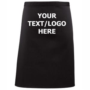 May include: A black apron with the text "YOUR TEXT/LOGO HERE" in white. The apron is a solid color and appears to be made of a durable fabric. The text is centered on the apron.