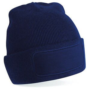 Puede incluir: Un gorro azul marino con un gran parche rectangular en blanco en la parte delantera. El gorro est&aacute; hecho de un tejido suave de punto.