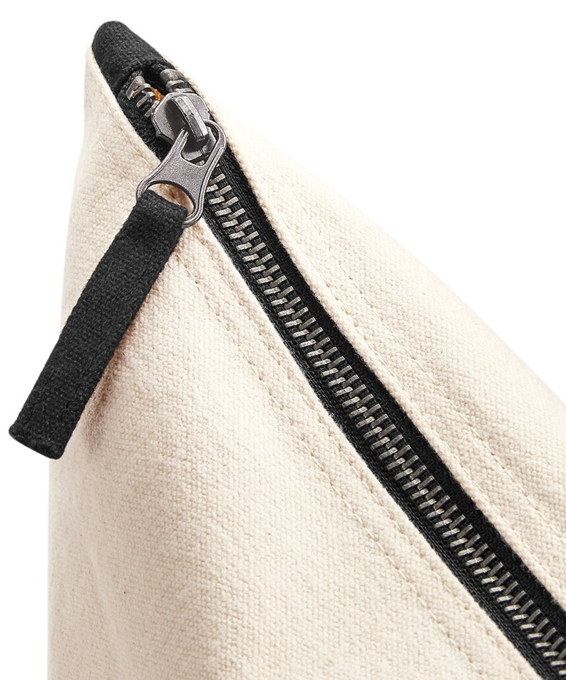 May include: Close-up of a white canvas zipper pouch with a black zipper and pull tab.