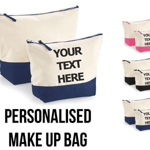 May include: Two personalized canvas makeup bags with a zipper closure. The larger bag is cream with a navy blue bottom and the smaller bag is cream with a pink bottom. Both bags have the text "YOUR TEXT HERE" printed in black.