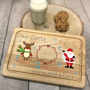 May include: Wooden serving board with a festive design for Santa. Features a reindeer, Santa Claus, and text that reads "Dear Santa" and "Lots of love Jacob & Darcie x". Includes a glass of milk and cookies.