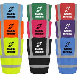 May include: Eight safety vests in different colors, including yellow, green, red, orange, pink, purple, black, and blue. Each vest has a reflective strip and a black symbol of a person with a hearing aid, with the text "HEARING IMPAIRED" below it.