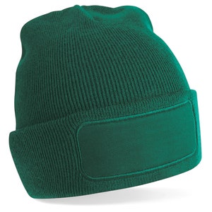 Puede incluir: Un gorro de punto verde oscuro con un parche rectangular grande en la parte delantera. El parche tambi&eacute;n es verde oscuro.