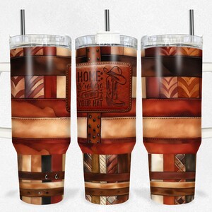 Könnte beinhalten: Ein Edelstahlbecher mit weißem Griff und Deckel. Der Becher hat ein Patchwork-Design aus braunem, beigefarbenem und rotem Leder mit einem braunen Leder-Patch, auf dem "Home is where you hang your hat" steht.