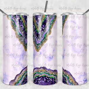 May include: A stainless steel tumbler with a purple, green, and gold agate design. The tumbler has a white marble background.