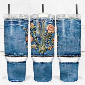 Puede incluir: Tres vasos de acero inoxidable con un patrón de mezclilla y un diseño bordado de cactus y flores. Los vasos tienen una tapa blanca y un asa blanca.