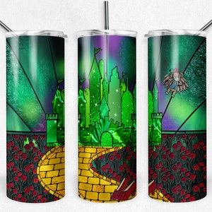 May include: A stainless steel tumbler with a green, yellow and red design featuring a castle, a yellow brick road and red poppies. The design is reminiscent of the Wizard of Oz.