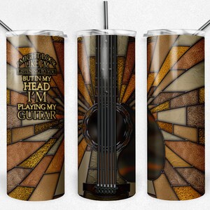 May include: A stainless steel tumbler with a colorful stained glass design featuring a guitar and the text "I might look like I'm listening to you but in my head I'm playing my guitar".