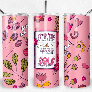 May include: Pink stainless steel tumbler with a floral pattern and the text "It's ok to not be ok. The sun will rise and we will try again. Self love matters!"