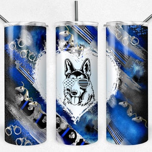 May include: A stainless steel tumbler with a blue and black design featuring a German Shepherd dog wearing sunglasses, a thin blue line flag, and handcuffs. The tumbler has a white heart shape with a blue watercolor background.