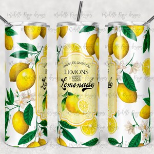 Puede incluir: Un vaso blanco con pajita, decorado con limones amarillos, hojas verdes y flores blancas. El texto "When life gives you lemons, make lemonade" está presente. Un artículo de bebida refrescante.