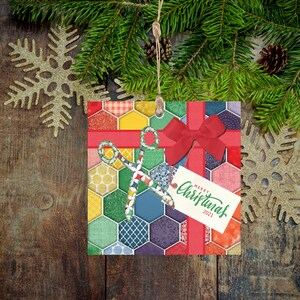 May include: A colorful Christmas ornament with a patchwork design featuring a red bow, a pair of scissors, and a tag that reads "Merry Christmas 2021".