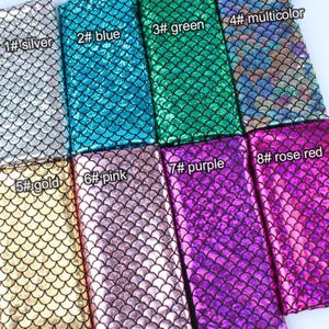 Könnte beinhalten: Nahaufnahme von acht Stoffmustern mit einem Fischschuppenmuster. Die Farben umfassen Silber, Blau, Grün, Mehrfarbig, Gold, Rosa, Lila und Rosenrot. Jede Probe ist mit einer Nummer und einem Farbnamen versehen.