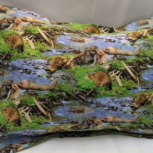 Könnte beinhalten: Ein Kissenbezug mit einem sich wiederholenden Muster von Bibern, die einen Damm in einem Bach bauen. Der Hintergrund ist hellblau mit grünem Laub und braunen Ästen.