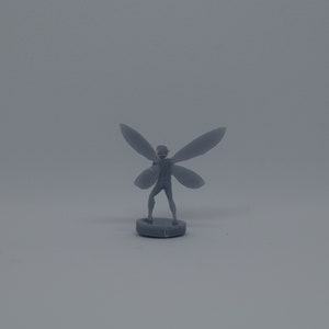 May include: A gray plastic miniature figurine of a fairy with wings outstretched. The fairy is standing on a round base.