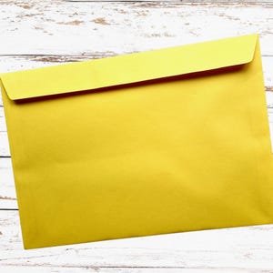 May include: A bright yellow envelope with a folded flap, set against a white wooden background. The envelope is rectangular and appears to be made of paper. The overall image is simple and clean, suitable for stationery or office supplies.