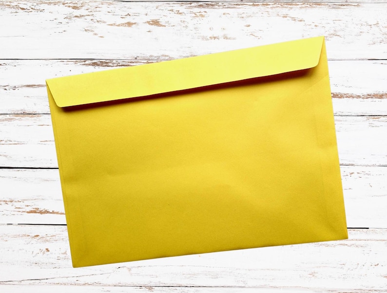 May include: A bright yellow envelope with a folded flap, set against a white wooden background. The envelope is rectangular and appears to be made of paper. The overall image is simple and clean, suitable for stationery or office supplies.