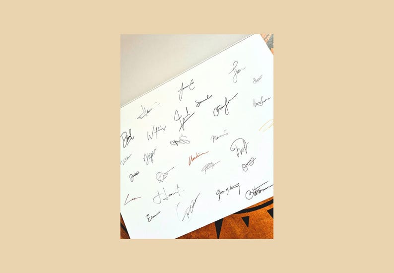 May include: A white sheet filled with numerous signatures in black ink. The signatures vary in style and size, with some appearing more elaborate than others. A few signatures are in red ink. The sheet is set against a neutral background.