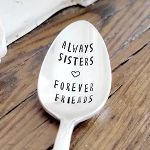 May include: Silver spoon with the words "Always Sisters Forever Friends" engraved on it. A small heart symbol is between the words "Sisters" and "Forever".
