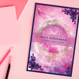 Op de afbeelding: Een roze en paarse journalomslag met een gouden geometrisch ontwerp en de tekst "SOUL ALIGNMENT 20 Week Guided Journal" en "Dina Visram".
