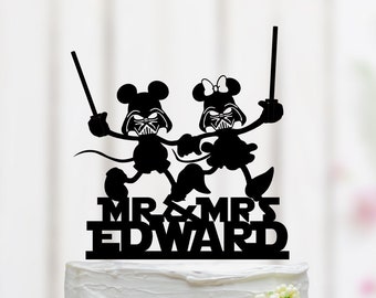 May include: Black and white silhouette of Mickey and Minnie Mouse dressed as Darth Vader, holding lightsabers. The cake topper says "Mr. & Mrs. Edward".