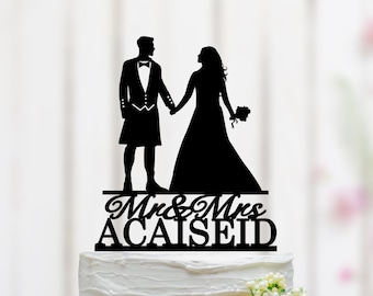 May include: Black silhouette cake topper of a bride and groom with the text "Mr. & Mrs. ACAISID" on a white cake.