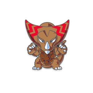 May include: A brown cartoon dinosaur pin with a red and brown head crest. The dinosaur has blue eyes, white claws, and a brown chest. The pin is set against a white background.