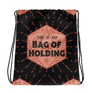 May include: Black drawstring bag with a red and white dice pattern. The dice has the text "This is my Bag of Holding" on it.
