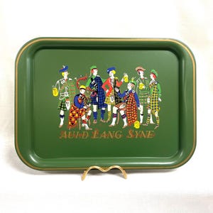 May include: Green rectangular serving tray with a gold trim and a colorful illustration of Scottish men in traditional attire. The words "Auld Lang Syne" are printed at the bottom.