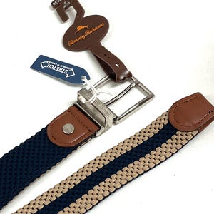 Puede incluir: Cintur&oacute;n reversible con dise&ntilde;o tejido en azul marino y beige. El cintur&oacute;n presenta una hebilla plateada y detalles de cuero marr&oacute;n. La etiqueta dice "Tommy Bahama" y "Stretch". Talla del cintur&oacute;n: 76-81 cm.