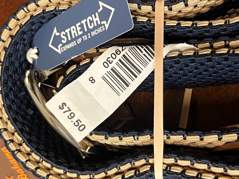 Puede incluir: Un cintur&oacute;n el&aacute;stico azul marino y beige con hebilla plateada. El cintur&oacute;n se extiende hasta 5 cm. Una etiqueta adjunta con la palabra "STRETCH" y el n&uacute;mero 8.