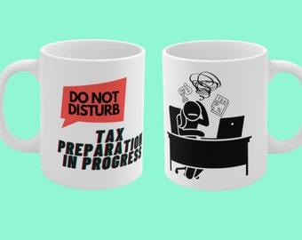 May include: White ceramic coffee mug with a red and black graphic that says "Do Not Disturb Tax Preparation in Progress". The other side of the mug has a black and white illustration of a person sitting at a desk with a laptop and papers, looking stressed.