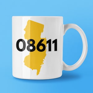 May include: White ceramic mug with a yellow outline of the state of New Jersey and the area code "08611" printed in black.