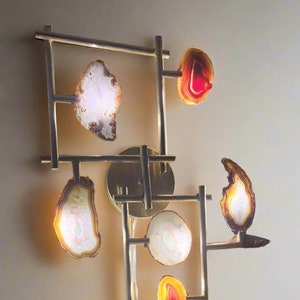 May include: A modern wall sconce with a geometric brass frame and agate slices in various colors, including red, orange, and white.