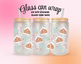 Op de afbeelding: Drie glazen bekers met bamboe deksels en roestvrijstalen rietjes. Elke beker heeft een herhaald patroon van peperkoekhuisjes, zuurstokken en kerstbomen. De tekst "Glass can wrap" staat bovenaan.