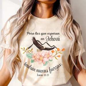 以下が含まれることがあります： クリーム色のTシャツ。鷲、山、花をあしらったグラフィックデザイン。スペイン語のテキストは「Pero los que esperan en Jehová tendrán nuevas fuerzas; Isaías 40:31」と書かれています。