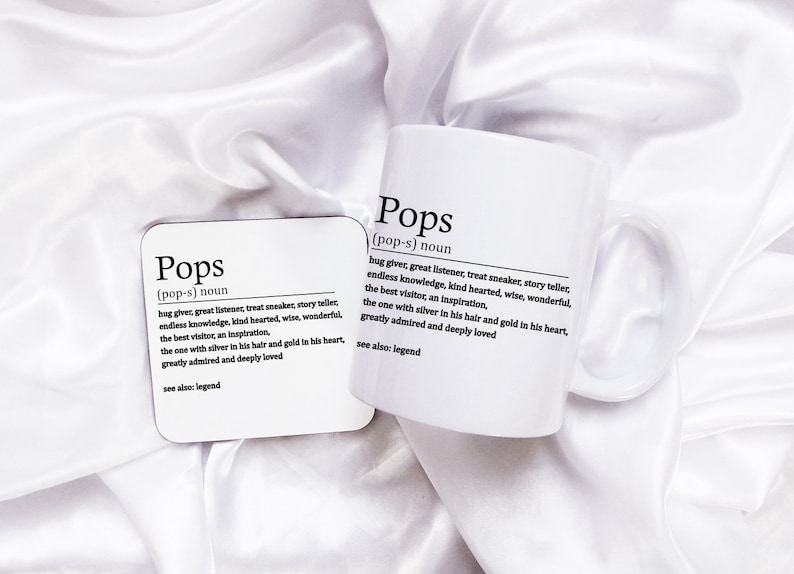 May include: White mug and coaster with the word "Pops" defined as "hug giver, great listener, treat sneaker, story teller, endless knowledge, kind hearted, wise, wonderful, the best visitor, an inspiration, the one with silver in his hair and gold in his heart, greatly admired and deeply loved. See also: legend."