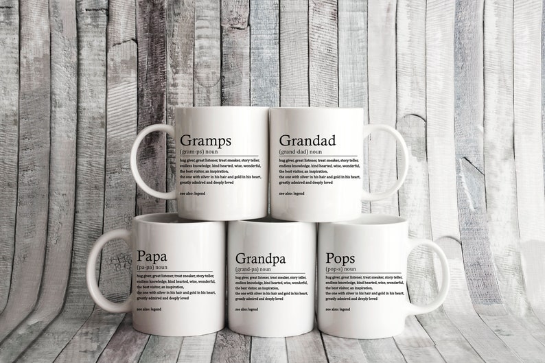 May include: Five white ceramic mugs with black text. Each mug has a different word on it: Gramps, Grandad, Papa, Grandpa, and Pops. The words are defined as a noun and the definition is written in black text below the word.