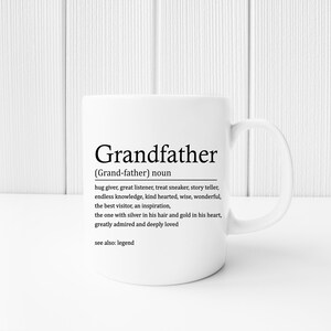 May include: White ceramic mug with a black graphic that reads "Grandfather (Grand-father) noun hug giver, great listener, treat sneaker, story teller, endless knowledge, kind hearted, wise, wonderful, the best visitor, an inspiration, the one with silver in his hair and gold in his heart, greatly admired and deeply loved see also: legend"