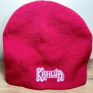 May include: A red knit beanie with the word "Kahlua" embroidered in white on the front.