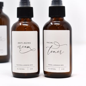 May include: Three amber glass bottles with white labels and black spray tops. The labels have black text that reads "Facial Toner", "Anti-Aging Cream", and "Facial Serum".