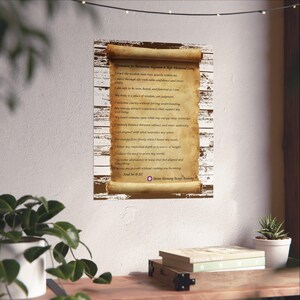 May include: A framed print featuring a scroll with affirmations for harmonious alignment and high vibrational living. The scroll is a parchment color with dark brown text and is set against a white and brown wooden background.